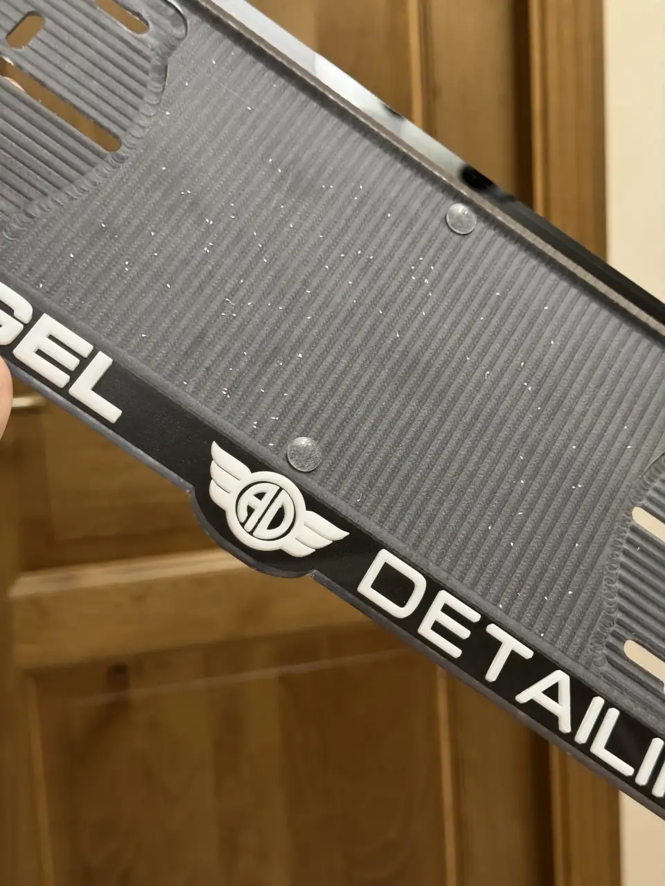 Angel Detailing · логотип крупным планом Макро номерной рамки Angel Detailing с крылатым логотипом