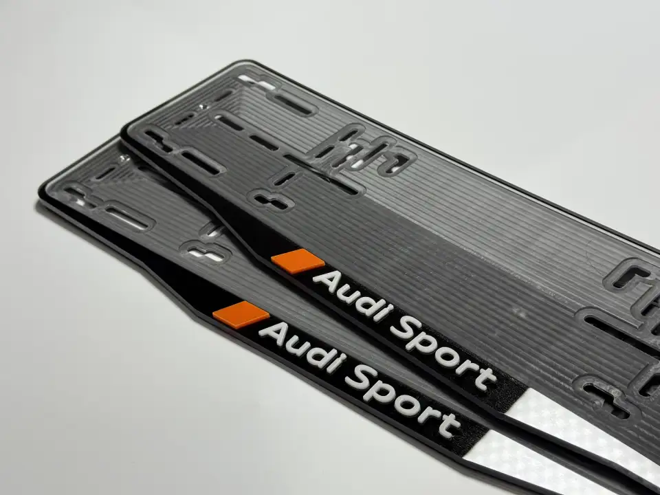 Audi Sport · надпись крупным планом Крупный план чёрной номерной рамки Audi Sport с белыми объёмными буквами