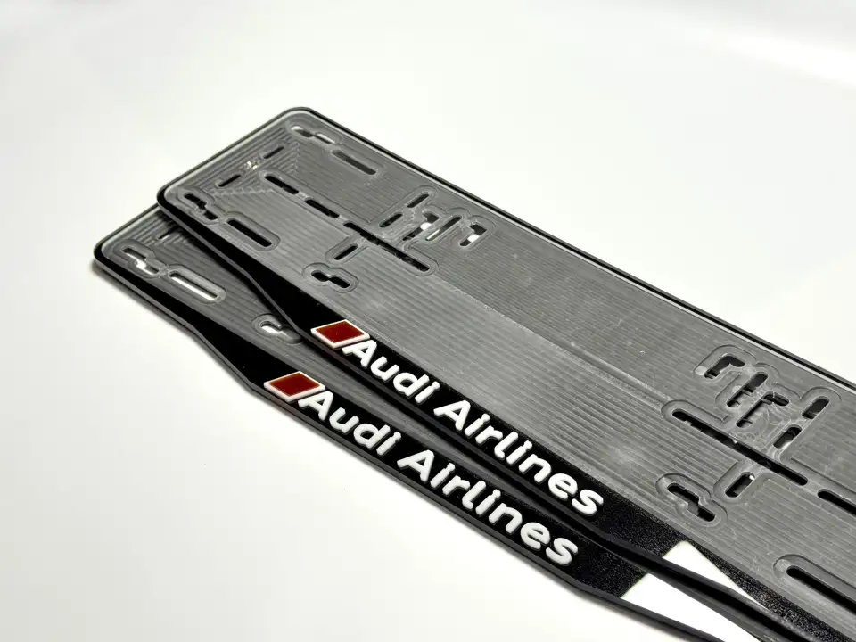 Audi Airlines · надпись крупным планом Крупный план чёрной номерной рамки Audi Airlines с объёмными белыми буквами