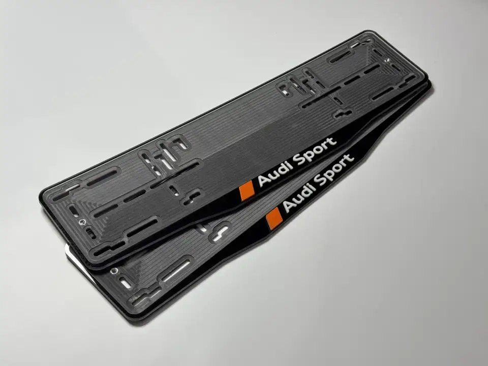 Audi Sport · чёрная пара, оранжевый акцент Пара чёрных номерных рамок Audi Sport с белыми буквами и оранжевым акцентом