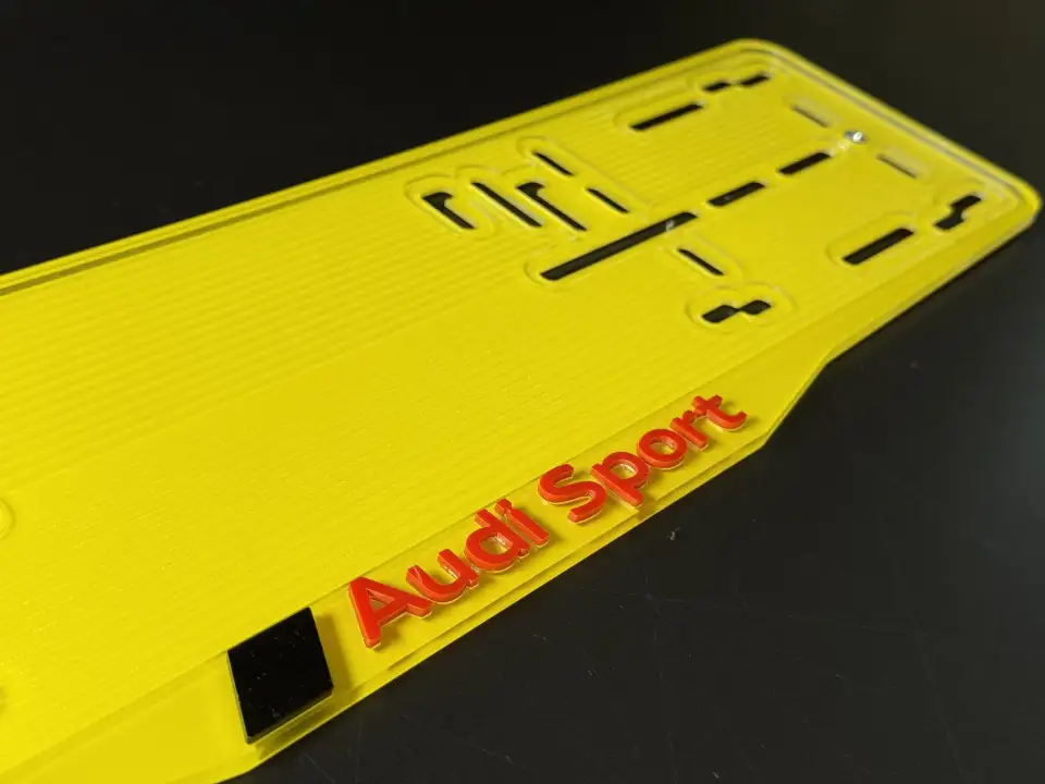 Audi Sport · макро красных букв на жёлтом Макро красных букв Audi Sport на жёлтой номерной рамке
