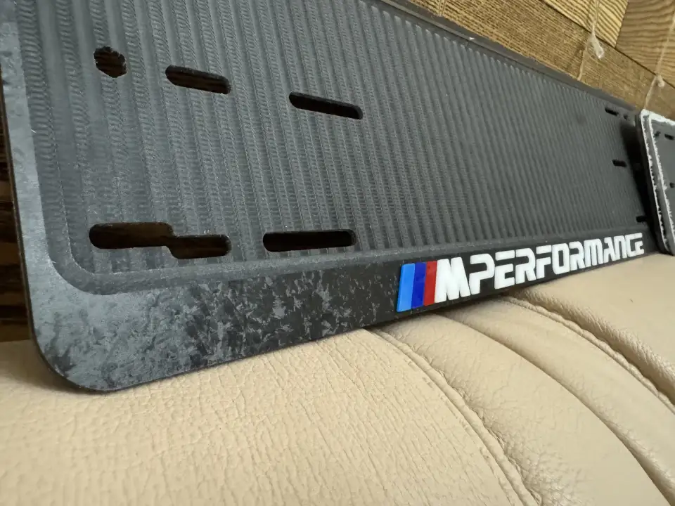 M Performance · крупный план эмблемы M Крупный план эмблемы M Performance на чёрной номерной рамке BMW