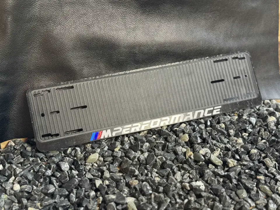 BMW M Performance · чёрная рамка с M-полосками Чёрная номерная рамка BMW M Performance с эмблемой M на гравии