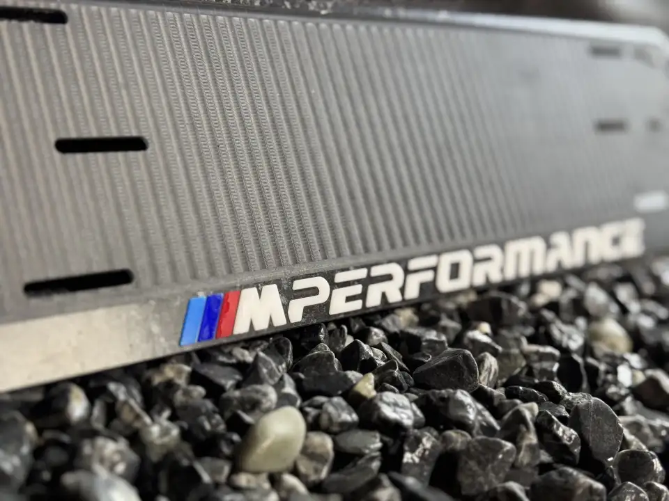 BMW M Performance · чёрная, макро логотипа Макро логотипа M Performance на чёрной номерной рамке BMW