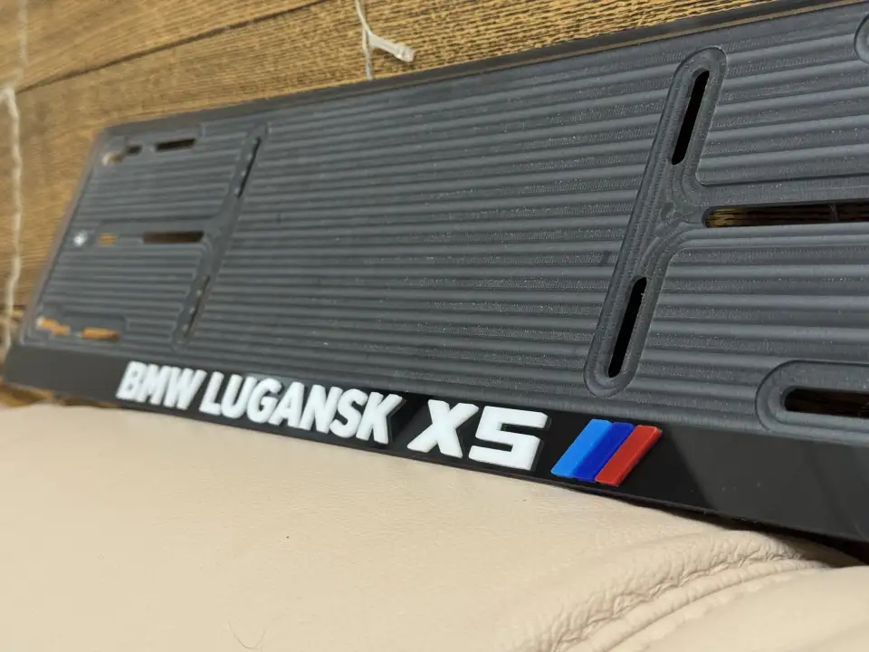BMW Lugansk X5 · надпись крупным планом Крупный план чёрной номерной рамки BMW Lugansk X5 с M-полосками