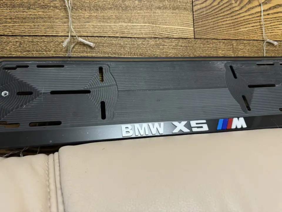 BMW X5 M · белые буквы, макро Крупный план надписи BMW X5 M на чёрной номерной рамке