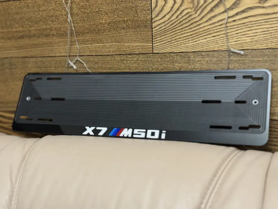 BMW X7 M50i · чёрный глянец, белые буквы Чёрная номерная рамка BMW X7 M50i с белыми буквами и полосками M