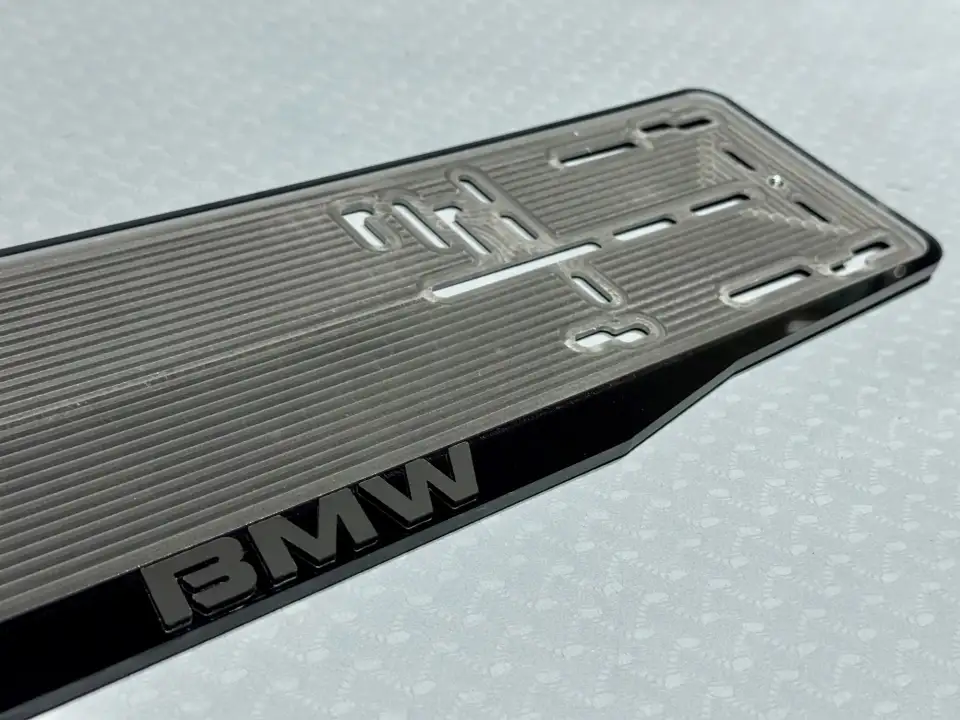 BMW · чёрные буквы, макро Крупный план чёрной надписи BMW на дымчатой прозрачной номерной рамке