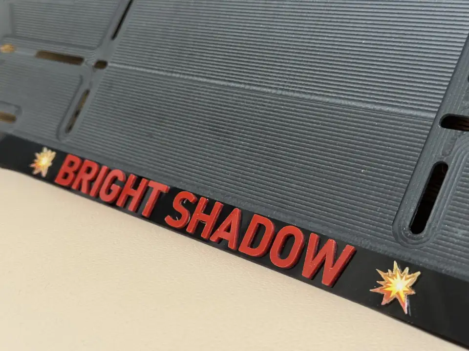 BRIGHT SHADOW · макро красных объёмных букв Макро чёрной номерной рамки с красными объёмными буквами BRIGHT SHADOW