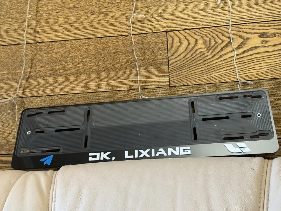 DK, LIXIANG · чёрная рамка, белые буквы Чёрная номерная рамка с надписью DK, LIXIANG и логотипом Li
