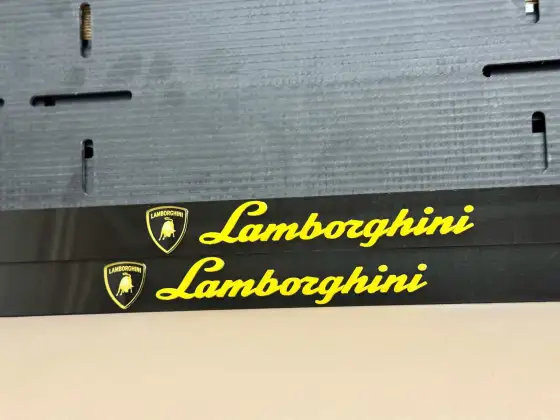 Lamborghini · комплект, чёрный глянец Две чёрные номерные рамки Lamborghini с жёлтыми буквами и золотым щитком