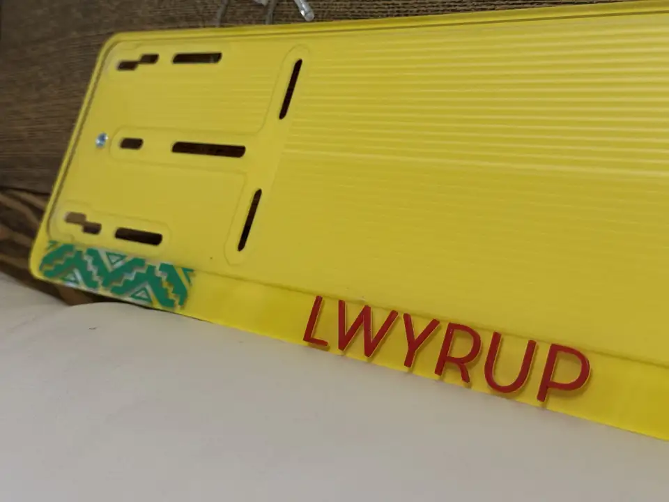 LWYRUP · надпись крупным планом Крупный план жёлтой номерной рамки LWYRUP с красными объёмными буквами