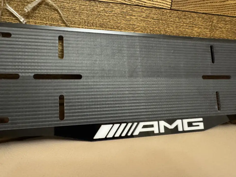 Mercedes-AMG · белая надпись AMG, макро Макросъёмка белой надписи AMG на чёрной номерной рамке Mercedes-AMG