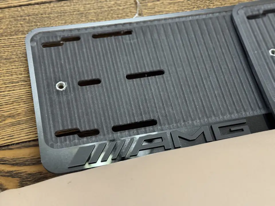 Mercedes-AMG · логотип крупным планом Макро номерной рамки Mercedes-AMG с объёмным логотипом на глянце
