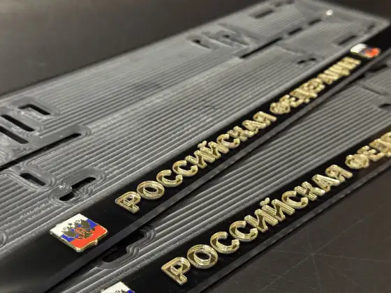Российская Федерация · золотые буквы и герб, макро Макросъёмка золотых букв Российская Федерация с гербом на чёрной номерной рамке