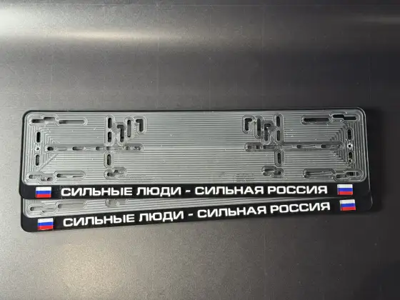 Чёрная номерная рамка с надписью Сильные люди - сильная Россия и флагом России