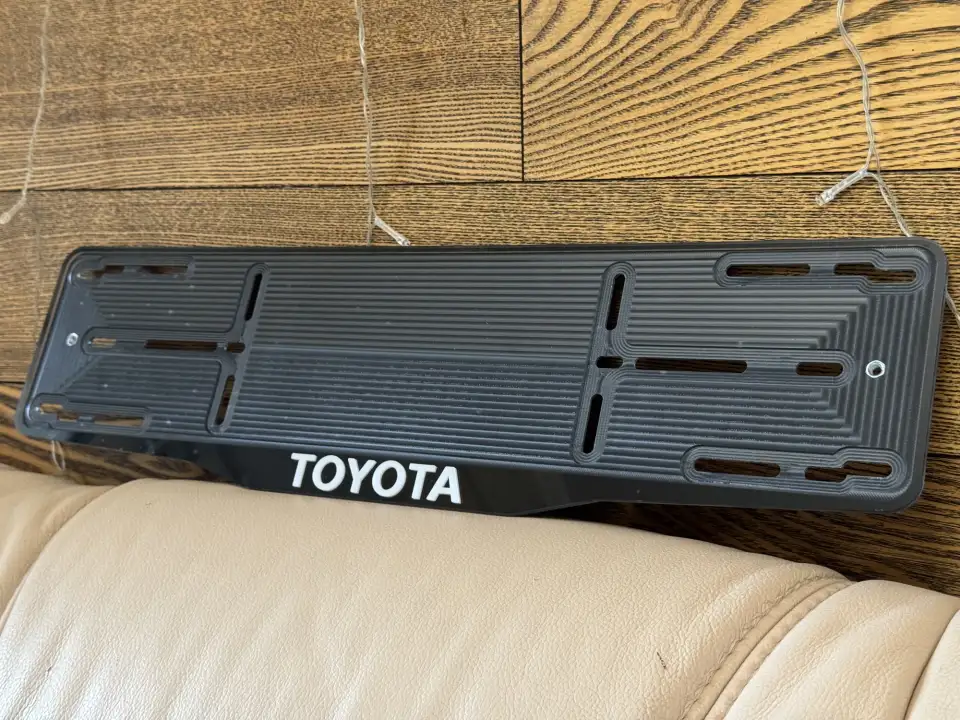 Toyota · чёрная рамка, белые буквы Чёрная номерная рамка Toyota с белыми объёмными буквами
