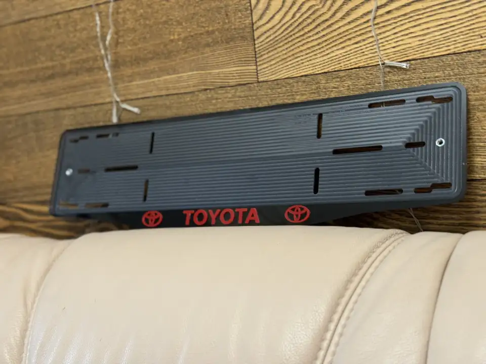 Toyota · чёрный глянец, красные буквы Чёрная номерная рамка Toyota с красными объёмными буквами и логотипами