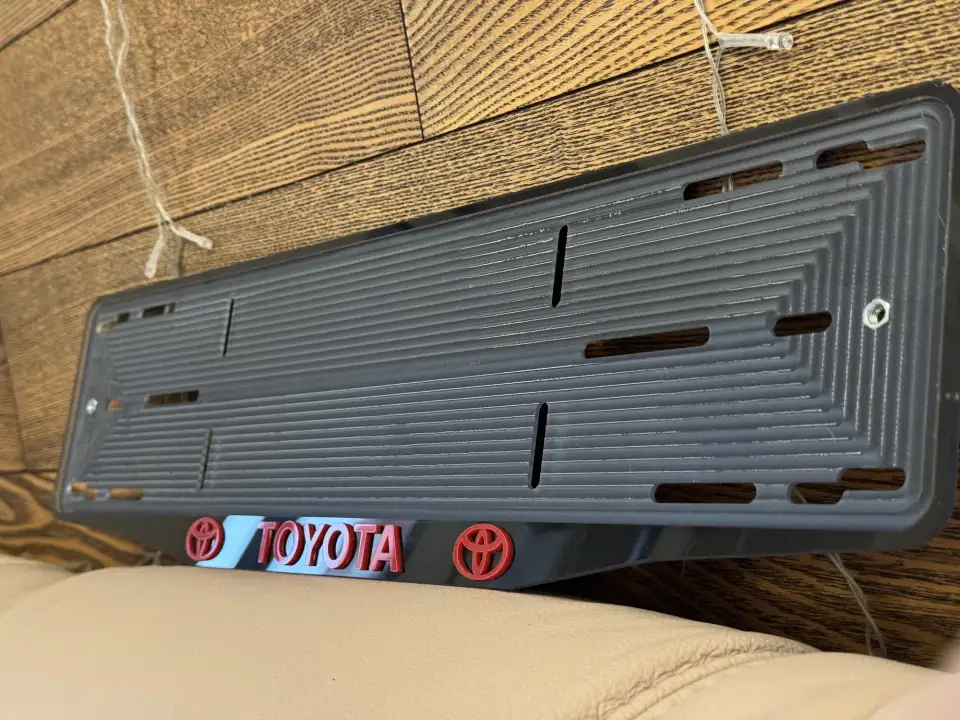 Toyota · чёрная рамка, красные буквы и логотип Чёрная номерная рамка Toyota с красными объёмными буквами и логотипом