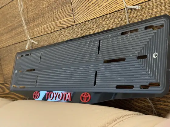 Чёрная номерная рамка Toyota с красными объёмными буквами и логотипом