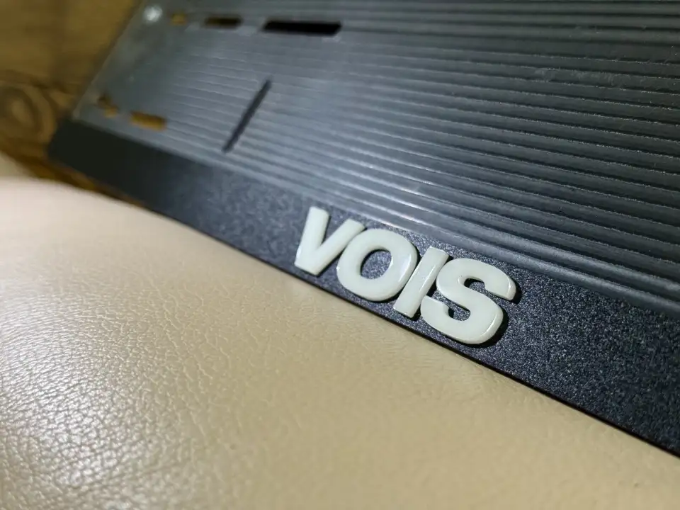 VOIS · белые объёмные буквы, макро Крупный план белой надписи VOIS на чёрной номерной рамке